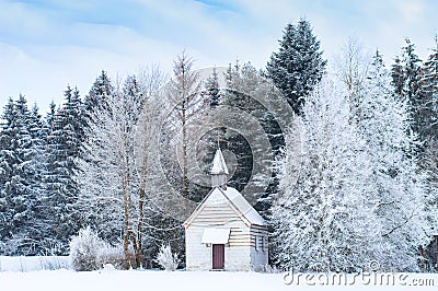 Small wooden chapel on snowbound frosty glade in snowy frozen forest Stock Photo