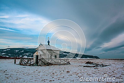 A small wooden Christian church stands among the snows and mountains. Stock Photo