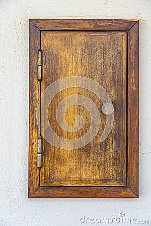 small wooden door inserted in the wall of a building to house an electricity meter or a water meter. Stock Photo