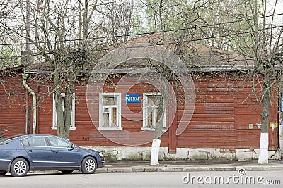 A small wooden house in an unknown village with a blue sign on which is written GAZPROM LLC. Editorial Stock Photo