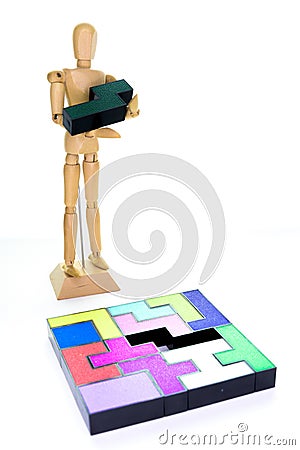 Small wooden mannequin holding the one piece needed to solve the puzzle, isolated on white background Stock Photo