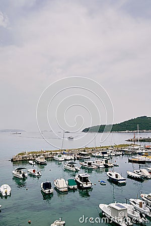 Small yachts are moored in rows at the pier against the backdrop of the mountains Stock Photo