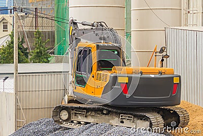 Small yellow excavator working at the construction site. Mini ba Editorial Stock Photo