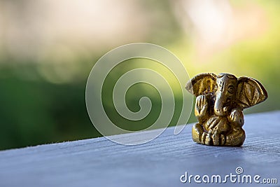Small yellow Ganesha figure with unfocused background. Beautiful golden Ganesh statue with open palm. Asian religion concept. Stock Photo