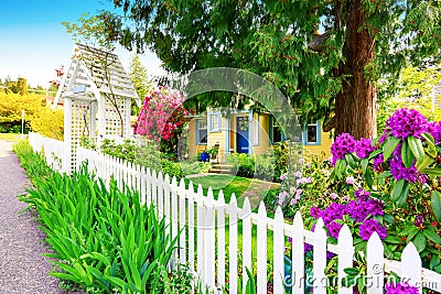 Small Yellow house exterior with White picket fence Stock Photo