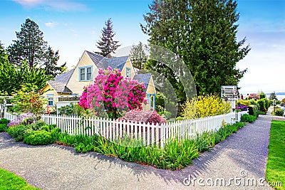 Small Yellow house exterior with White picket fence Stock Photo