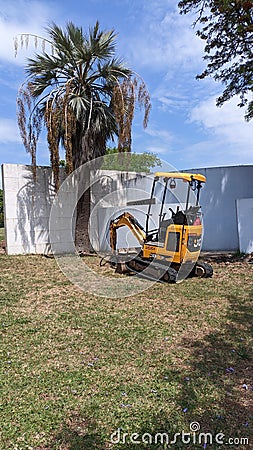 16.04.2023 A small yellow mini excavator with a bucket is excavating in a park in Lisbon Editorial Stock Photo