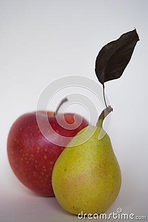 Small yellow pear with brown leaf together at a red apple Stock Photo