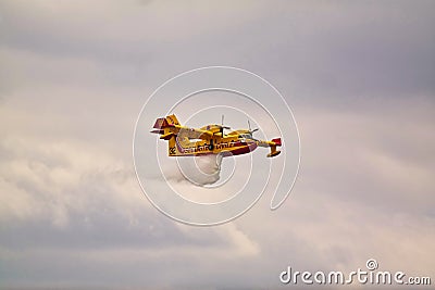 Small yellow red seaplane hydroplane flying in the sky droping water Editorial Stock Photo
