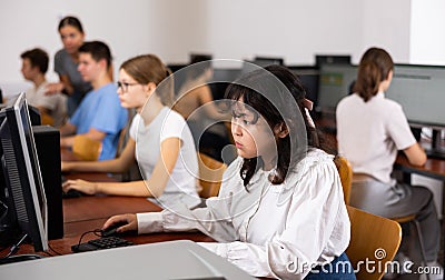 Focused Asian female teenager solving tasks of computer science in the auditory Stock Photo