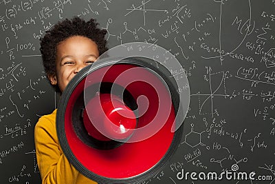 Smart black child with megaphone loudspeaker on chalkboard background with science formulas Stock Photo