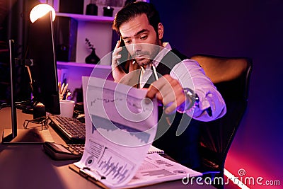 Smart businessman calling partner on smartphone writing memo. Surmise. Stock Photo