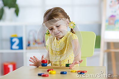 Little child girl plays in kindergarten in Montessori preschool class. Stock Photo