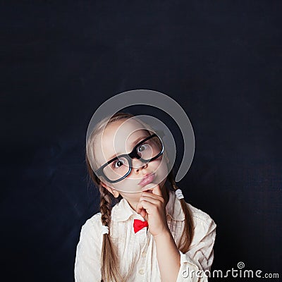 Smart child thinking. Little girl in glasses on chalk board Stock Photo