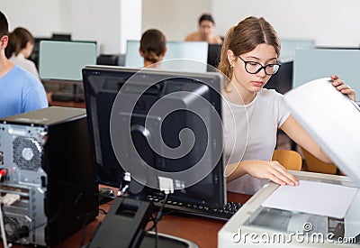 Clever female teenager solving tasks of computer science, using pc and printer in the auditory Stock Photo