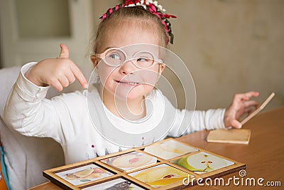 Smart girl with Down syndrome collects puzzles Stock Photo