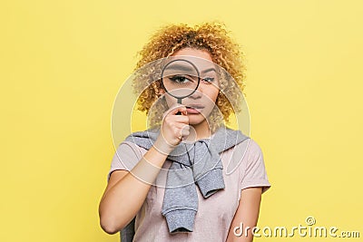 Smart girl is looking to camera through a loupe. She is investigating something. Young woman is serious and calm Stock Photo