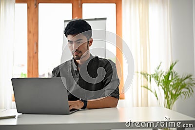 Smart and handsome asian male office worker or tech engineer using laptop computer Stock Photo