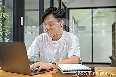 Smart Asian male office worker or tech engineer working at his desk, using laptop Stock Photo