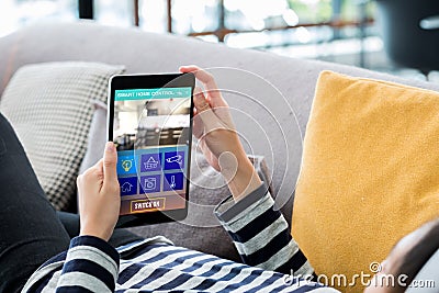 Smart home automation control concpet.Woman lying down on sofa using tablet control device in home.digital technology lifestyle Stock Photo