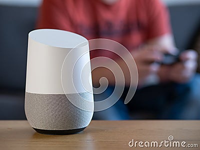 Smart home voice activated speaker in lounge with gamer in background Stock Photo