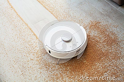 Smart House. Vacuum cleaner robot runs on wood floor in a living room Stock Photo