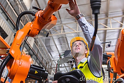 Smart modern engineer male using modern robot technology. Robotic welding arm setup in automation production process in factory Stock Photo