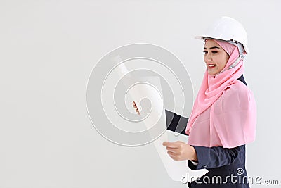 Smart muslim young asian woman wearing blue suit smiling confident holding blueprint in studio. Isolated white background portrait Stock Photo