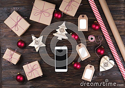 Smart phone with christmas presents on wooden background top view. Online holiday shopping concept. Flat lay, text space. Internet Stock Photo