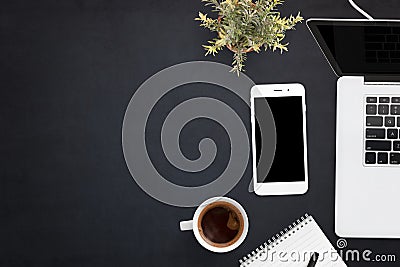 Smart phone and laptop on black office desk with copy space on left side Stock Photo