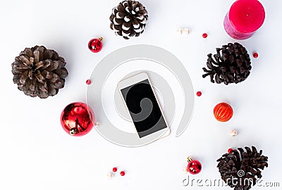 Smart phone mobile display on table with isolated white screen for mockup in Christmas time. cones and decorations in background. Stock Photo