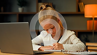 Smart pretty primary schoolgirl blonde little pupil seven years old kid studying in house room writing homework doing Stock Photo