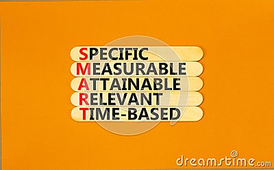 SMART symbol. Concept words SMART specific measurable attainable relevant time-based on stick. Beautiful orange background. Stock Photo
