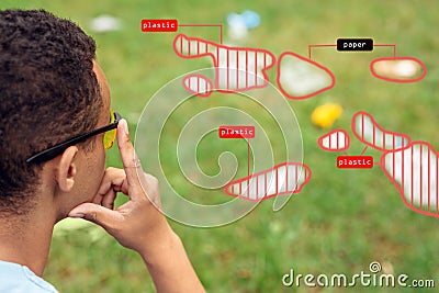 Smart Waste Sorting. African boy wearing digital glasses sitting in the park looking at grass pensive using app for Stock Photo
