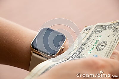 smart watch on the girl& x27;s hand took dollar bills on the street, money Stock Photo