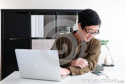 Smart youngadult 40s asian man with eye glasses working on laptop or computer notebook in modern working space. office life and Stock Photo