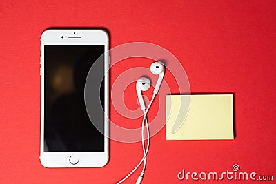 Smartphone with Blank Screen Connects to Earphones with Spiral Cable on Red Background Top View Stock Photo