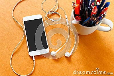 Smartphone with blank screen, gadjet in cup and earphones on woo Stock Photo