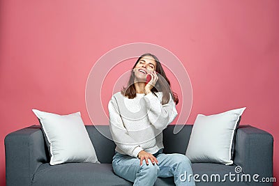 Smartphone call. Friendly laughing young woman chatting with friend on phone, sharing good news, sitting on sofa Stock Photo