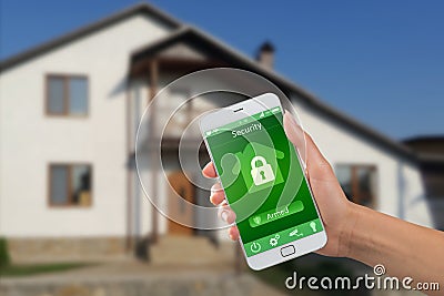 Smartphone with home security app in a hand on the building background Stock Photo