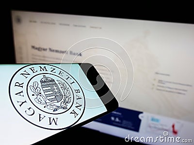 Smartphone with logo of Hungarian National Bank (Magyar Nemzeti Bank, MNB) on screen in front of website. Editorial Stock Photo
