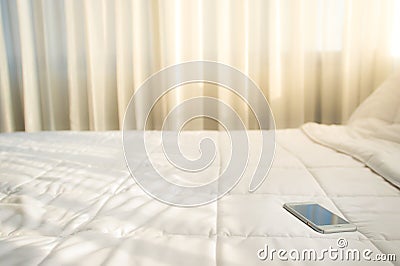 The smartphone is placed on a bed with a white sheet Stock Photo