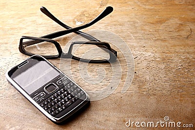 Smartphone with qwerty keypad and pair of eyeglasses Stock Photo