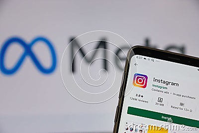 The smartphone screen on which the Instagram application is installed against the background of the Meta Facebook logo. There is a Editorial Stock Photo