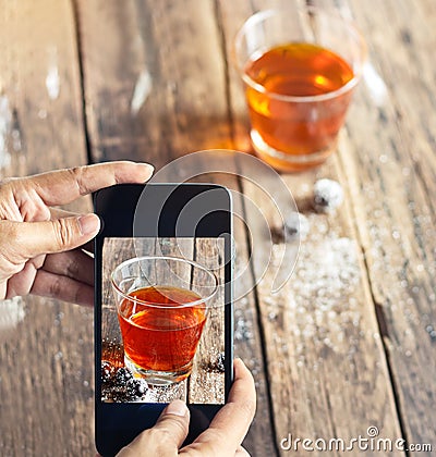 Smartphone take photos of tea and grape on wooden background, vibrant concept Stock Photo