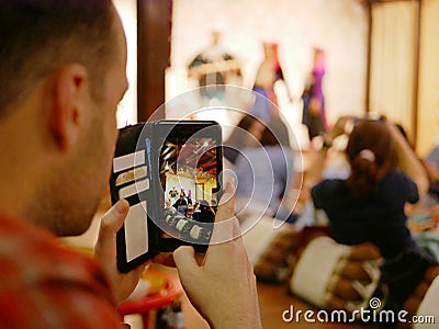 A smartphone on a tourist`s hands taking a photograph of Northern Thai dancing performing on a stage Editorial Stock Photo