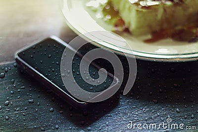 Smartphone with water drops on food wood table Stock Photo