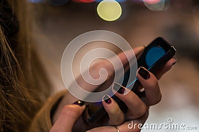 Smartphone in woman hands in front of blurred city lights Stock Photo