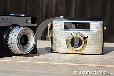 Smena 8M and Penti I old vintage golden cameras on wooden background Editorial Stock Photo