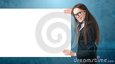 Smile Business woman portrait with blank white board on blue isolated. Female model with long hair in glasses. Stock Photo